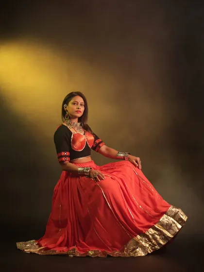 A confident and poised shot that showcases the beautiful festive outfit. The lighting highlights the vibrant colours and intricate details of her traditional clothing.