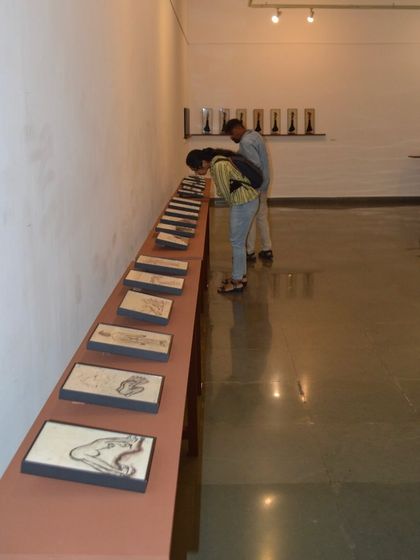 Visitors closely observing the details of the reverse paintings from the exhibition. The intimate scale of the works invites close looking.
