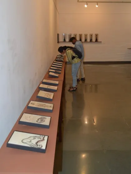 Two visitors studying the linear arrangement of the small reverse paintings.