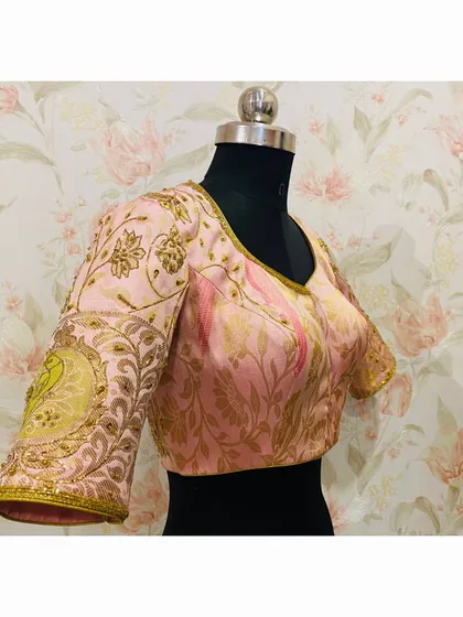 A side view of the pink brocade blouse, showing the intricate hand embroidery on the sleeve, including a large peacock motif.