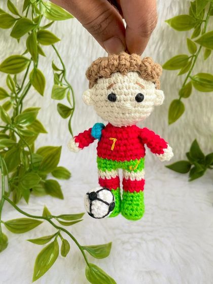 A mini replica doll of the football superstar Cristiano Ronaldo, CR7! This keychain-sized doll is ready for the field with his jersey and a tiny football.