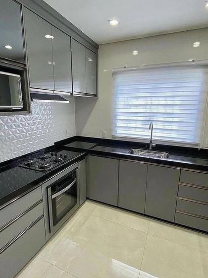 A view of the compact yet efficient L-shaped section of the Vasant Kunj kitchen. The design incorporates a built-in oven, hob, and microwave, all within easy reach of the main work area.