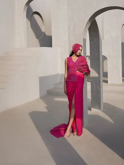 A modern interpretation of the sari in a bold pink hue, featuring a draped jacket element and a high-slit skirt for a fusion-forward edge.