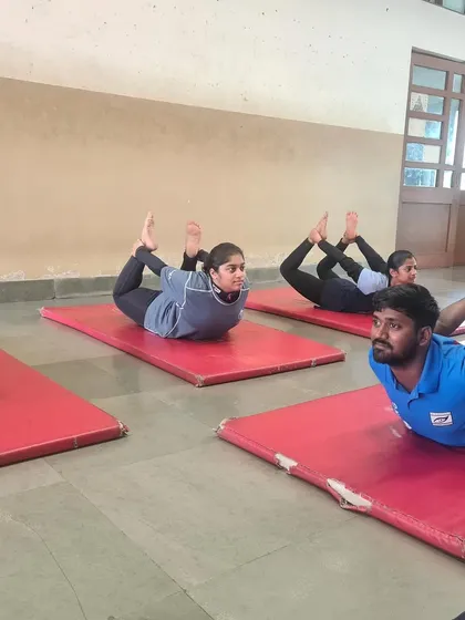 My athletes and coaches practicing the Dhanurasana (bow pose) during a yoga session. This demonstrates our commitment to physical conditioning that directly benefits a shooter's stability and core strength.