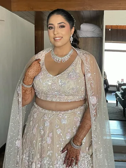 A smiling bride with her pearl-studded messy ponytail. This hairstyle is perfect for a sangeet or engagement party.