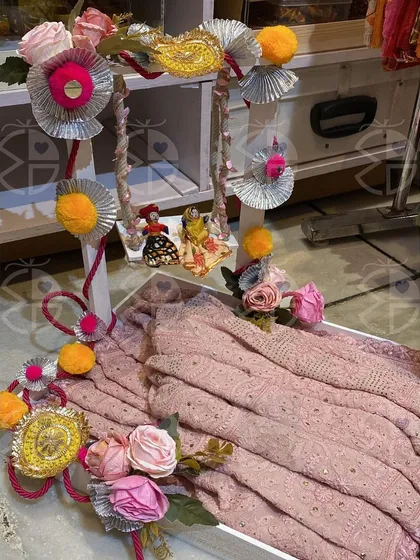 Getting ready for Teej with this exquisite gifting solution. A pink 'phulkari' is beautifully arranged in a decorative tray with a miniature swing, creating a stunning visual.
