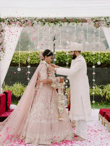 The groom places the garland on his bride during the Varmala ceremony, a key moment in their beautiful outdoor wedding.