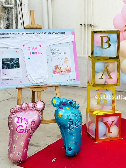 A close-up of the baby shower details, including 'It's a Girl' and 'It's a Boy' balloons, 'BABY' blocks, and a custom board with the baby's sonogram.