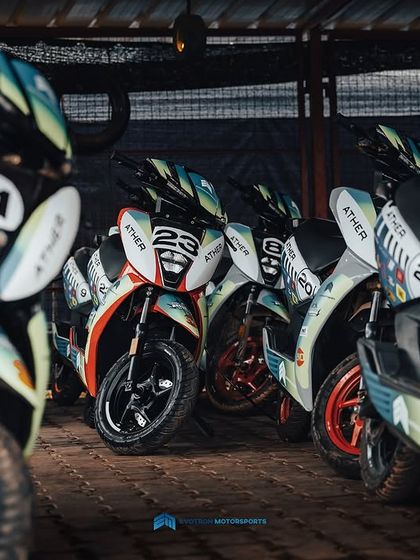 A fleet of race-prepped Ather electric scooters parked in the garage. Each one is numbered and ready for the amateur and pro races.