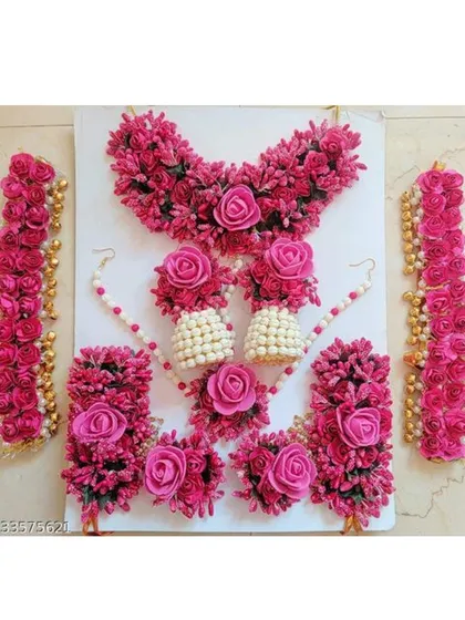 A complete floral jewellery set in bright pink, laid out to show all the matching pieces: necklace, earrings, hath phool, and maang tikka.