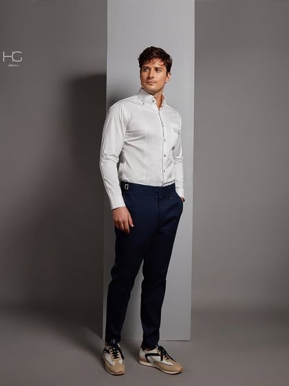 A full-length view of the pocket-detail white shirt, paired with navy trousers and sneakers for a smart-casual interpretation.