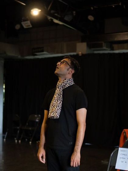 An actor looking up at the lighting rig during a shoot. The high, industrial ceiling and exposed trusses are part of Vyoma's unique character.