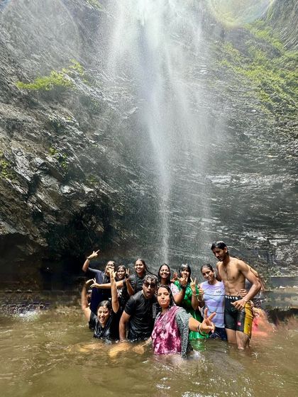 A group having a fantastic time in the natural pool of a waterfall on our coastal trip. I always ensure safety while allowing for maximum fun.
