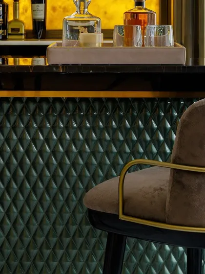 The bar chair is seen here against the quilted green leather front of the bar, showing how we love to mix textures and colors to create a rich, layered look.