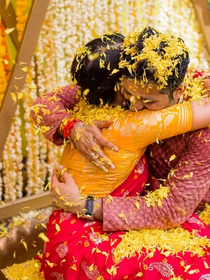 A warm hug amidst a shower of yellow petals. This photo from Aayushi and Bharat's Haldi captures the emotion and connection at the heart of the celebration.