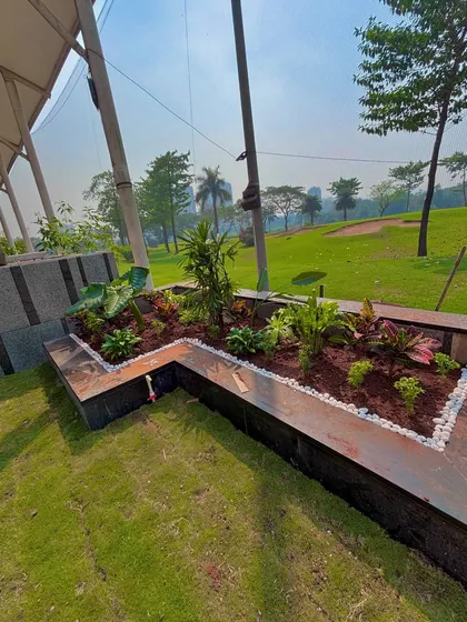 The finished planter beds at the Lodha villa, filled with a variety of plants and edged with white pebbles. This modern design element sits beside a freshly laid lawn.