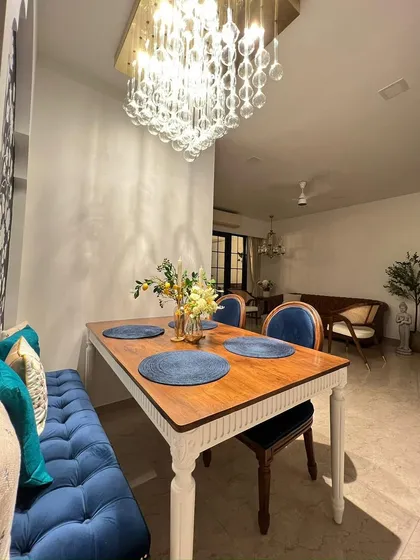 A beautiful dining nook featuring my custom-made dining table with a solid wood top and white painted legs, paired with a plush tufted blue velvet bench. This setup shows how I can tailor furniture to fit unique spaces.