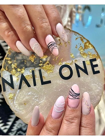 A unique and modern design featuring a matte nude and pink base with delicate black and white thread art. This look combines different textures and minimalist lines for a sophisticated finish.