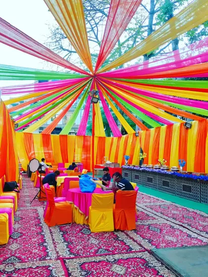 A wide view of the 'welcome baby' party tent, showcasing the cheerful and celebratory atmosphere created with multi-coloured drapes.