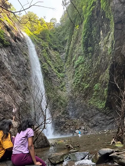 Two trekkers sitting by Koodluthirtha Falls.