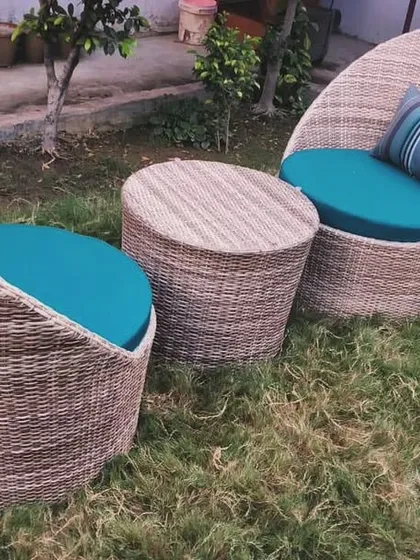 This two-seater coffee set features unique, deep-seated "cup" chairs made from woven wicker. Paired with a matching wicker table and vibrant teal cushions, this set is perfect for a small balcony or a cozy garden corner, offering a stylish and comfortable spot for two.