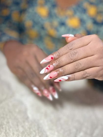 A Valentine's themed French manicure with white tips, red swirls, and tiny heart accents. This is a fun and romantic design.