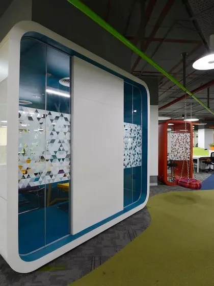 A meeting pod with rounded corners and a clean white finish, creating a futuristic look. These pods are placed throughout the open office to provide on-demand private space.