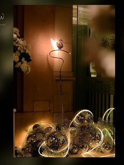 A decorative swan lamp surrounded by disco balls and baby's breath, a quirky and artistic lighting element.