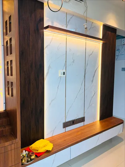 A TV unit that combines a white marble-finish backdrop with dark wood panels. The integrated LED strip lighting around the panel creates a beautiful ambient effect, making it a focal point.