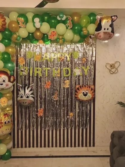 A simple jungle-themed decoration perfect for home celebrations. This setup includes a balloon arch with animal head foil balloons and a silver fringe curtain for the backdrop.