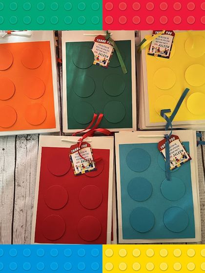The handmade paper bags for the LEGO-themed party, shown in five bright colors: orange, green, yellow, red, and blue.