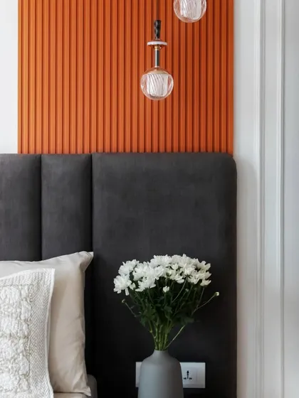 A detail shot of the color-blocked master bedroom, showing the contrast between the charcoal grey headboard and the vibrant burnt orange panel.