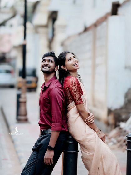 A fun, back-to-back pose against a street pole in a charming city lane.