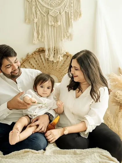 A sweet, interactive moment. The parents' loving gaze on their child tells a beautiful story of family connection.