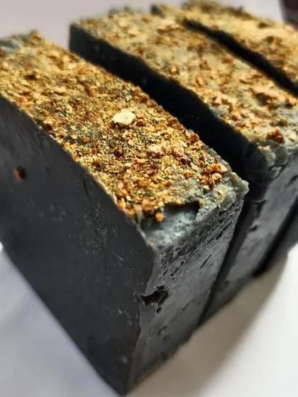 A close-up texture shot of the Charcoal Orange soap bars, highlighting the natural, rustic finish of a handcrafted product.
