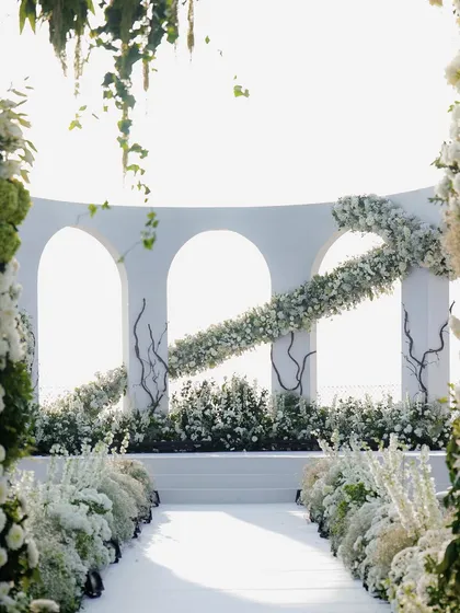 The interplay of light and shadow on the white floral structures. The design was carefully planned to look beautiful in the bright sunlight, with hanging greenery and layered flowers creating depth and texture.