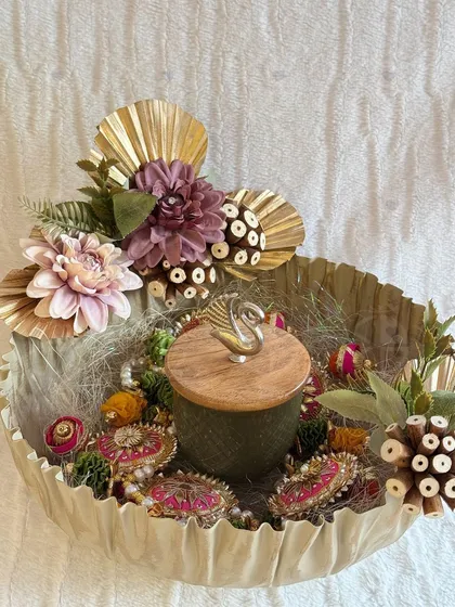 A rustic and earthy Diwali hamper. This unique bowl is filled with decorated 'rakhis' and other festive items, adorned with dried flowers and natural elements.