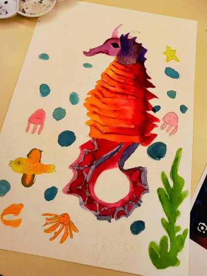 A close-up of a finished watercolor seahorse. The students learned blending and layering techniques to create the vibrant red and orange scales.