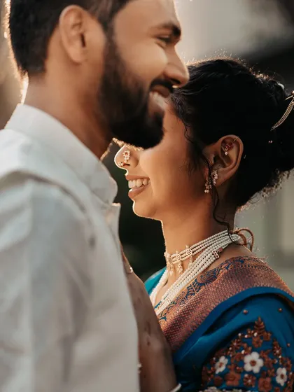 A sun-kissed close-up capturing the bride's radiant smile and the beautiful details of her traditional Maharashtrian jewelry.