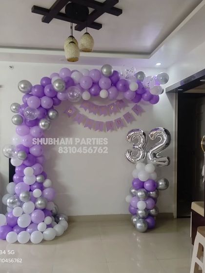 A purple and silver balloon arch for a 32nd birthday celebration at home.