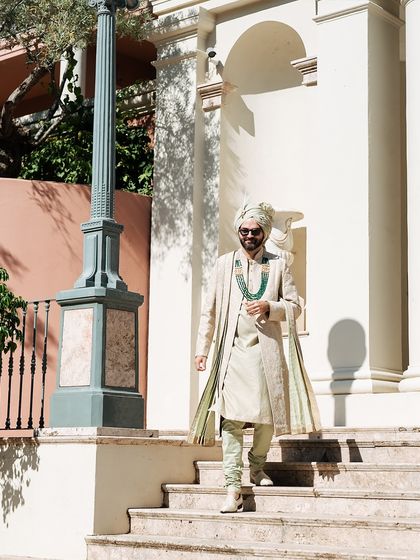 A confident stride down the steps in Marbella. The groom's open-jacket Tarun Tahiliani sherwani was chosen to be both stylish and comfortable for a warm destination wedding.