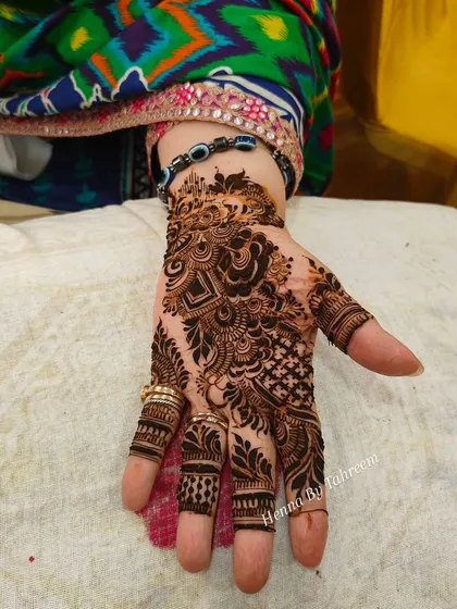 This thick belt or "patta" style is a bold and beautiful choice for party mehendi. The design focuses on a dense pattern across the back of the hand, leaving the fingers detailed but lighter.