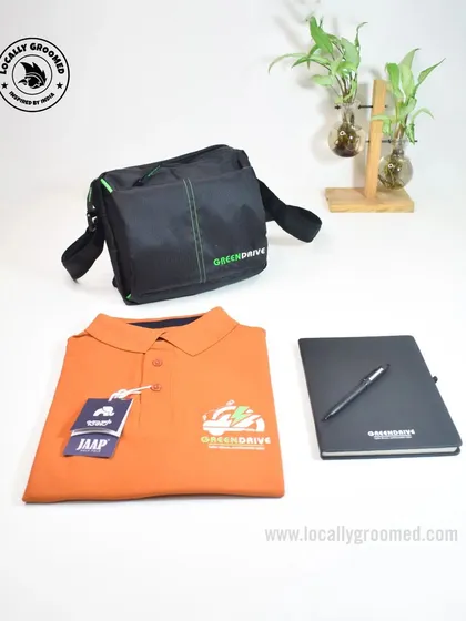 A simple yet effective welcome kit for Greendrive, featuring a branded orange polo shirt, a black notebook and pen, and a functional sling bag.