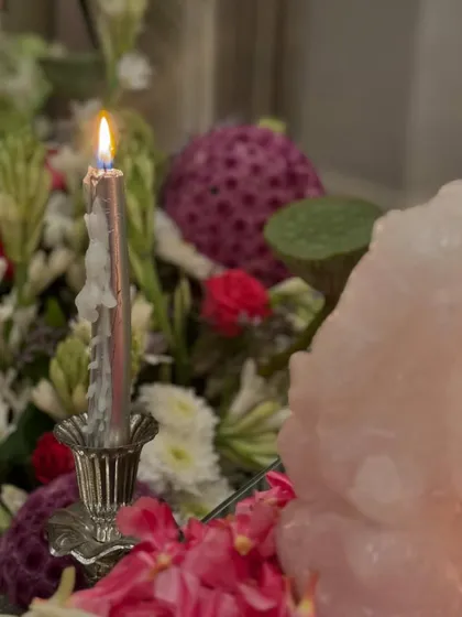 Seeking blessings on the first day of Navratri with this floral arrangement. The soft glow of a candle illuminates a display of lotus pods, tuberoses, and a rose quartz Ganesha, creating a serene and spiritual mood.