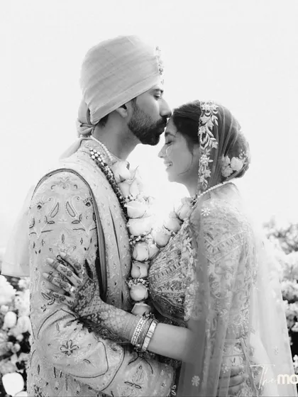 A tender black and white moment. The groom kisses his bride's forehead, a classic gesture of love and affection, beautifully captured with a soft, timeless feel.