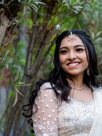 A happy, smiling bride surrounded by nature. The soft makeup look is perfect for an outdoor sangeet or reception.