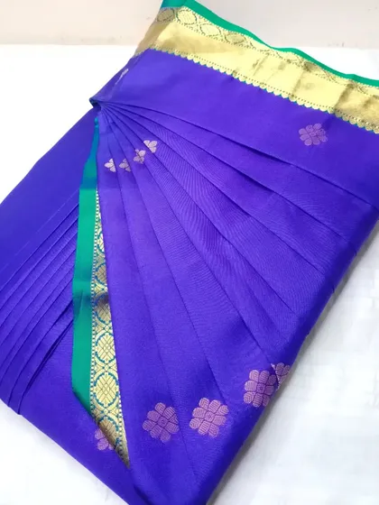 A royal blue and green silk saree, pleated and ready to be draped.