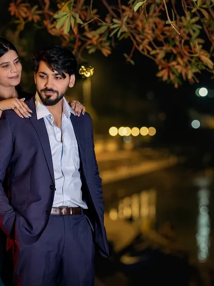 A classic, stylish pose by the riverside at night. The way she looks at him, with the gentle lights creating a soft ambiance, makes for a timeless and elegant pre-wedding portrait.