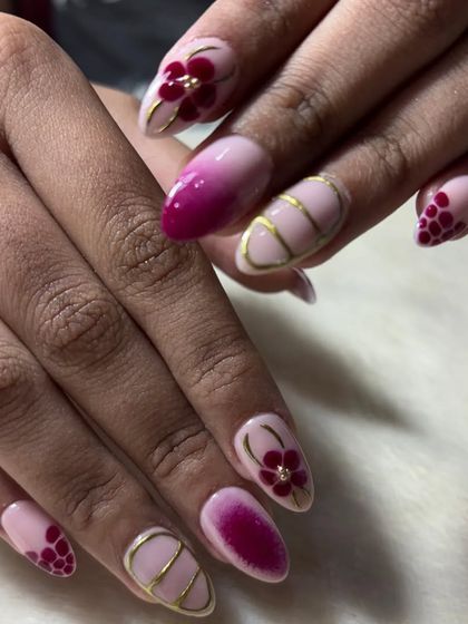 A beautiful and intricate floral nail art design. This look combines a magenta ombre, gold line art, and delicate, hand-painted flowers for a stunning result.