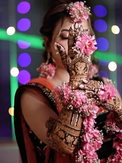 A stunning shot of a bride with floral jewelry that complements her intricate mehendi design, which features a Ganesha portrait.